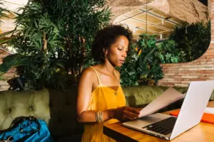A freelance digital marketing expert working on a gig on her laptop while holding a file folder